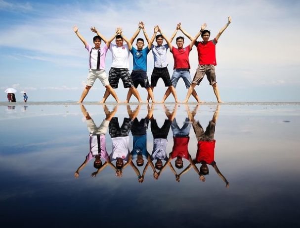 A group of Atria Tourist's young travelers cheers on the beach, basking in the sunny joy.