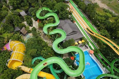 Bird's-eye view of a lively water park with a big green slide, promising fun and excitement!