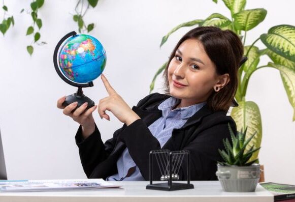 A business woman holds a globe, representing Atria Tourist, a top travel agency.