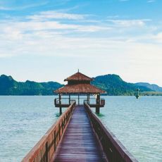 Explore Atria Tourist's scenic travel spots with a wooden pier leading to a serene island in the ocean.