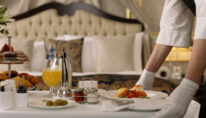 A man in white gloves carefully sets up a breakfast table for guests at Atria Tourist.