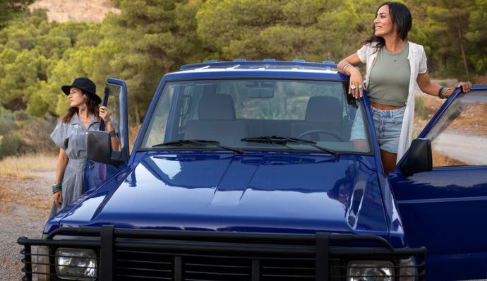 Two women pose by a blue truck for Atria Tourist, your top tour agency.